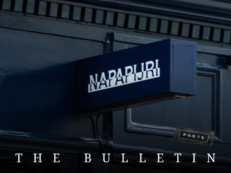 Napapijri storefront sign mounted on dark blue exterior wall.