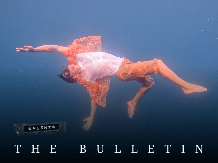Underwater swimmer floating horizontally wearing patterned shirt and shorts