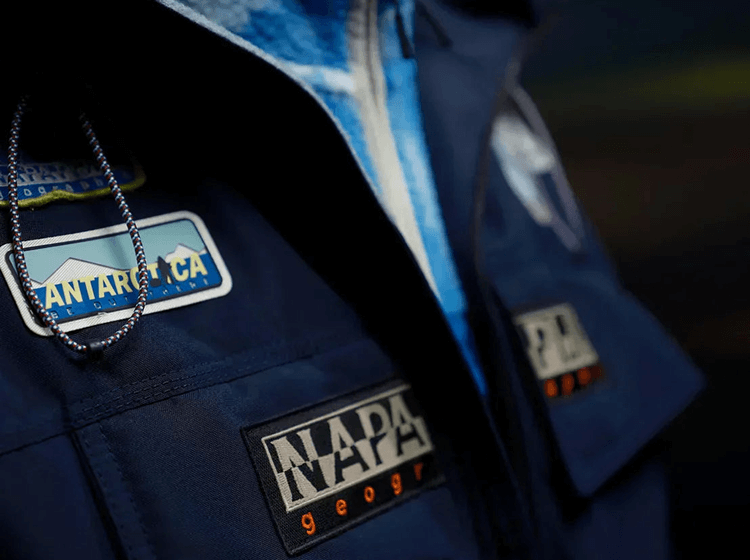 Close-up of Napapijri Geographic logo patch on blue fabric background