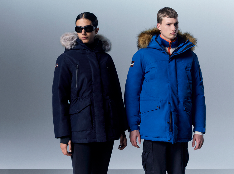 Two people wearing Napapijri winter jackets with fur-trimmed hoods in studio.