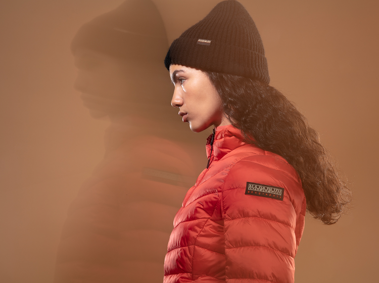 A person  wearing  red Napapijri padded jacket with black knit beanie.