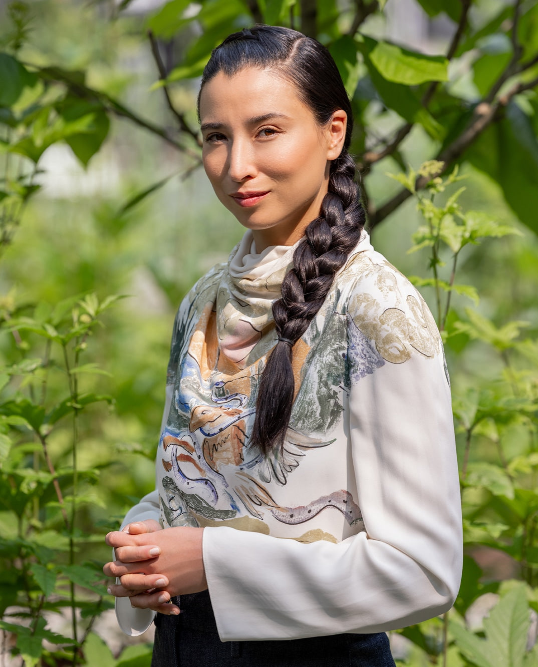 Portrait of a person with braided hair wearing a printed top in a park