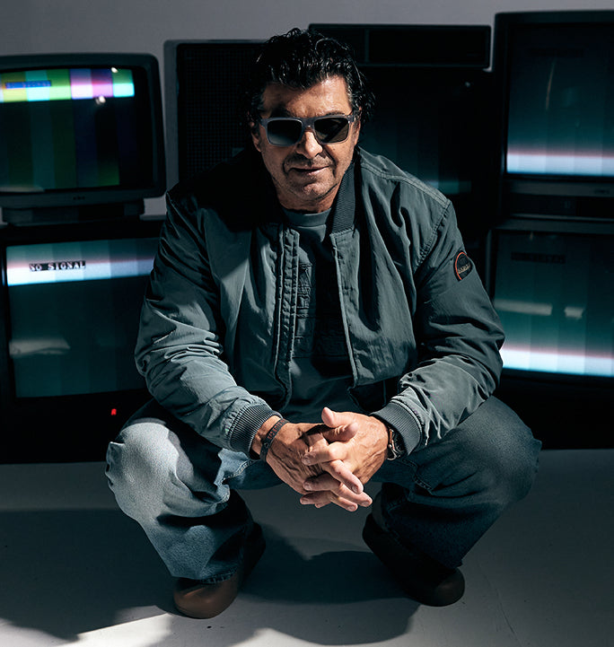 Alberto Tomba seated in studio wearing grey Napapijri jacket surrounded by monitors