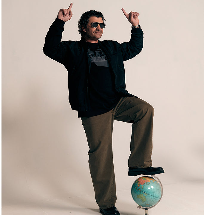 Alberto Tomba balancing on globe wearing casual jacket and trousers