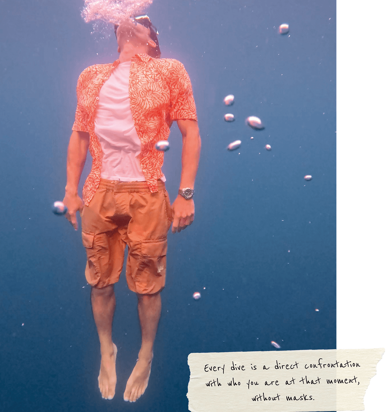 Underwater free diver wearing patterned shirt and cargo shorts mid-descent