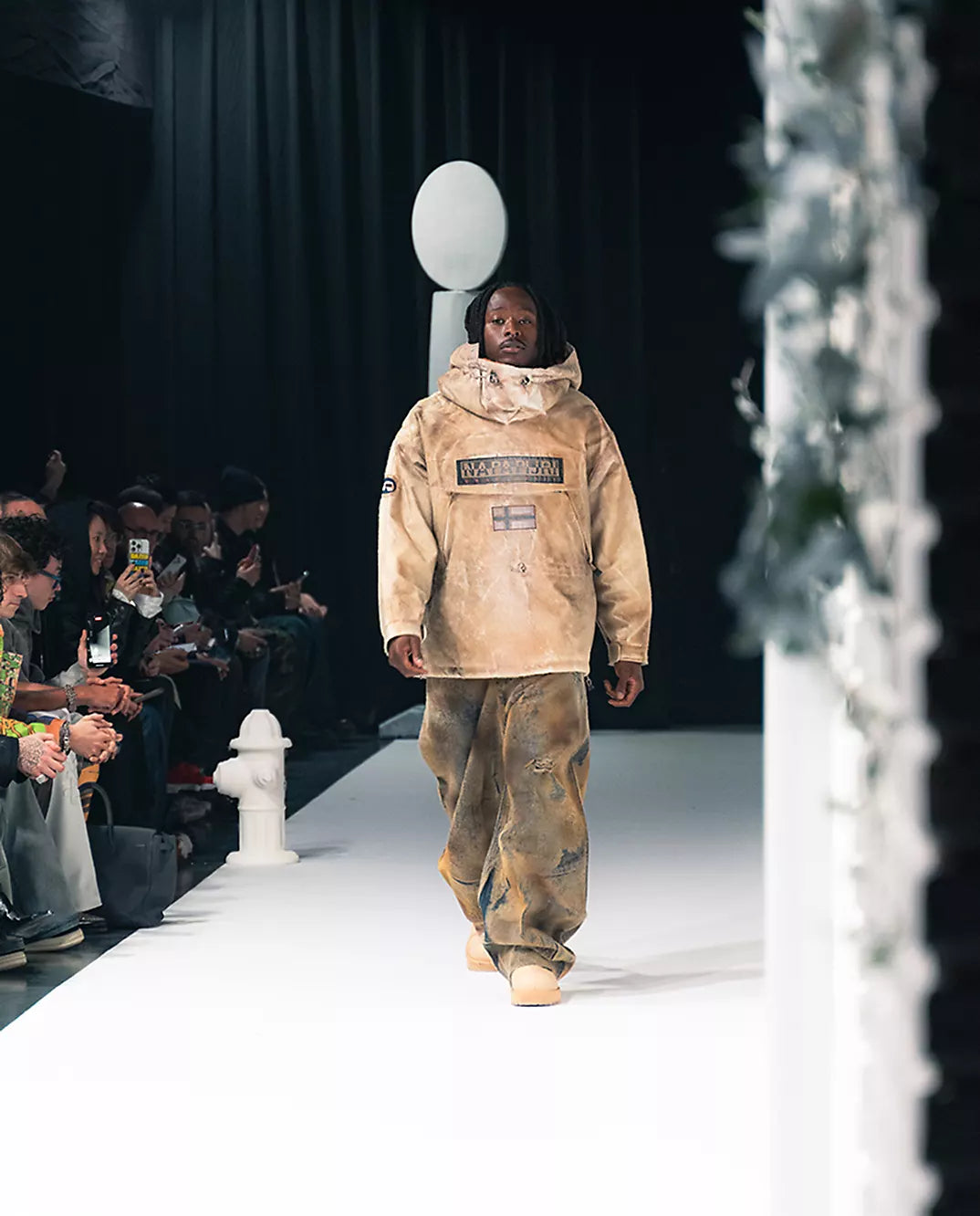 A person wearing Napapijri beige anorak walking the runway during fashion show.