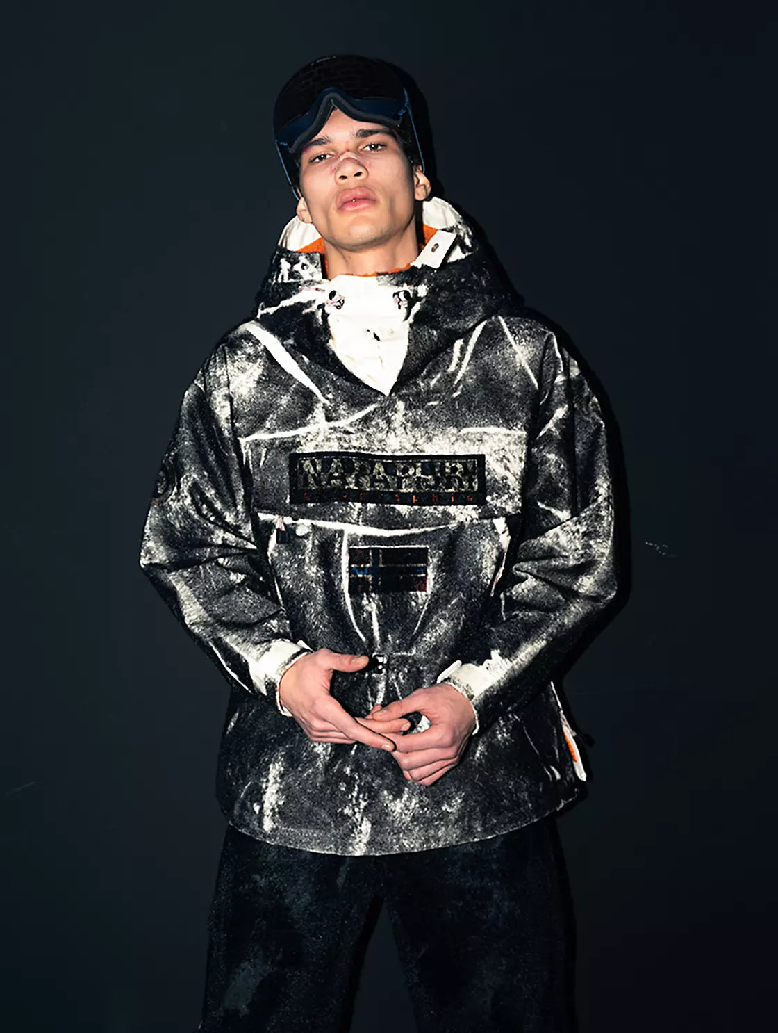 A person wearing Napapijri marbled hooded jacket with logo chest patch.