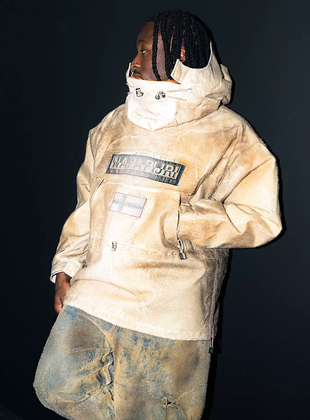 A person wearing Napapijri beige anorak highlighting hood and chest branding.